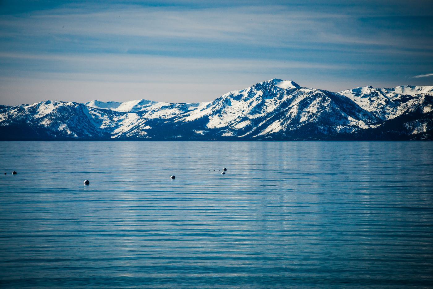 Snow-covered mountains across a calm blue Lake Tahoe